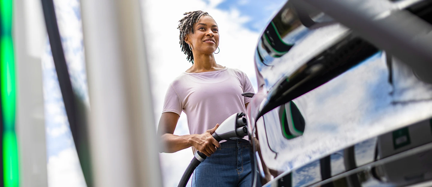 Woman smiling while charging electric car 