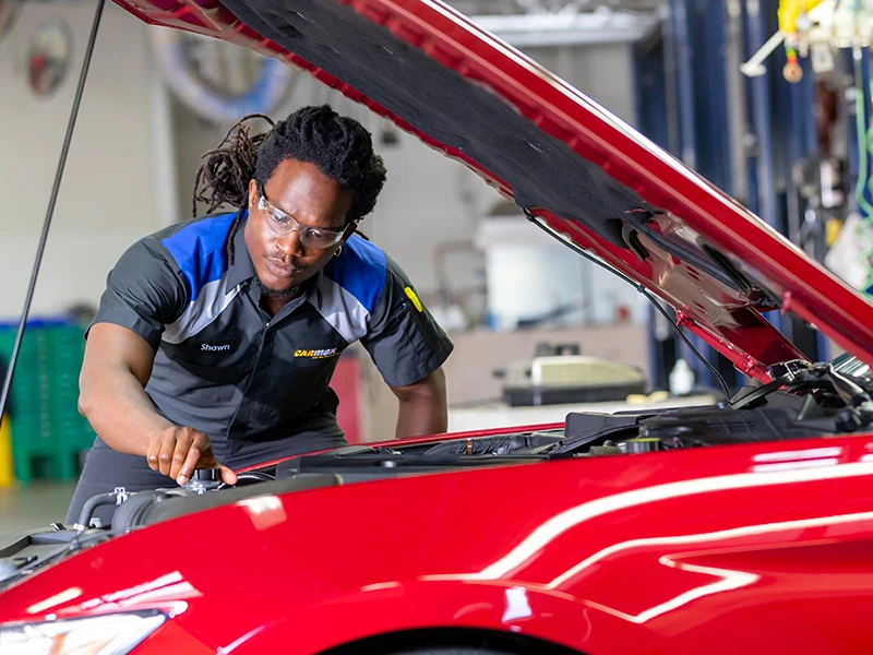 Getting Used Cars Ready to Sell: Auto technician working under the hood of car 