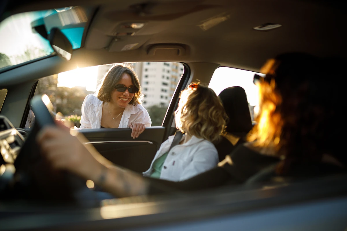 Friends speaking to pedestrian outside car