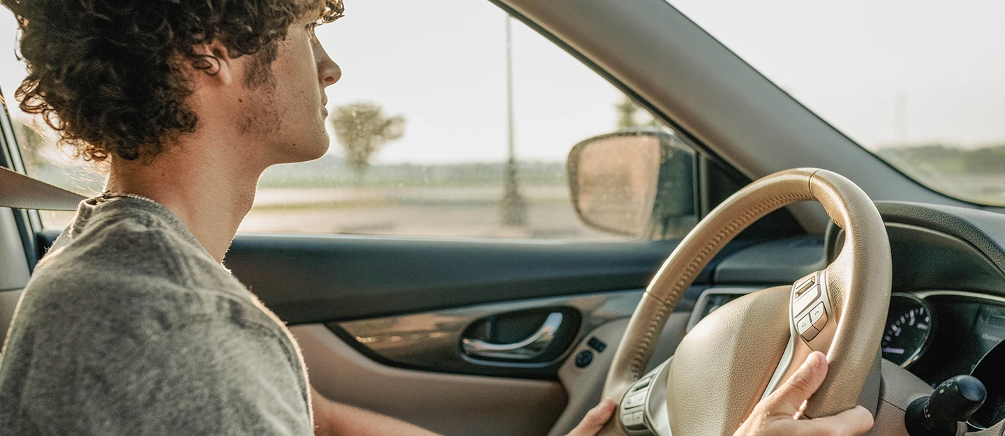 Man driving with both hands on steering wheel staring out the windshield 