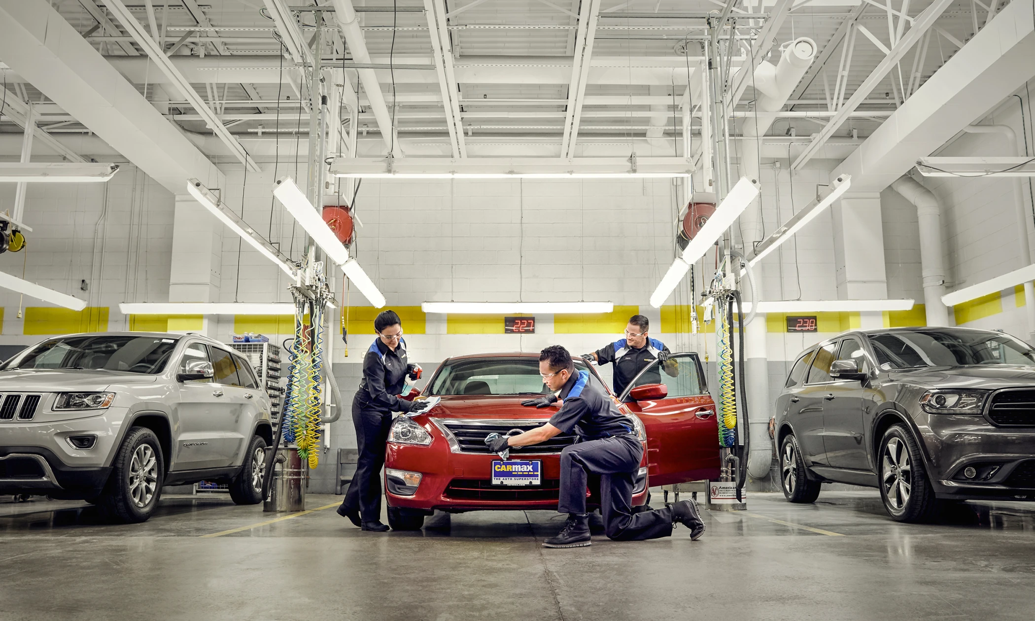 MaxCare, Explained: CarMax Service center employees shining up a red sedan in the service center | CarMax