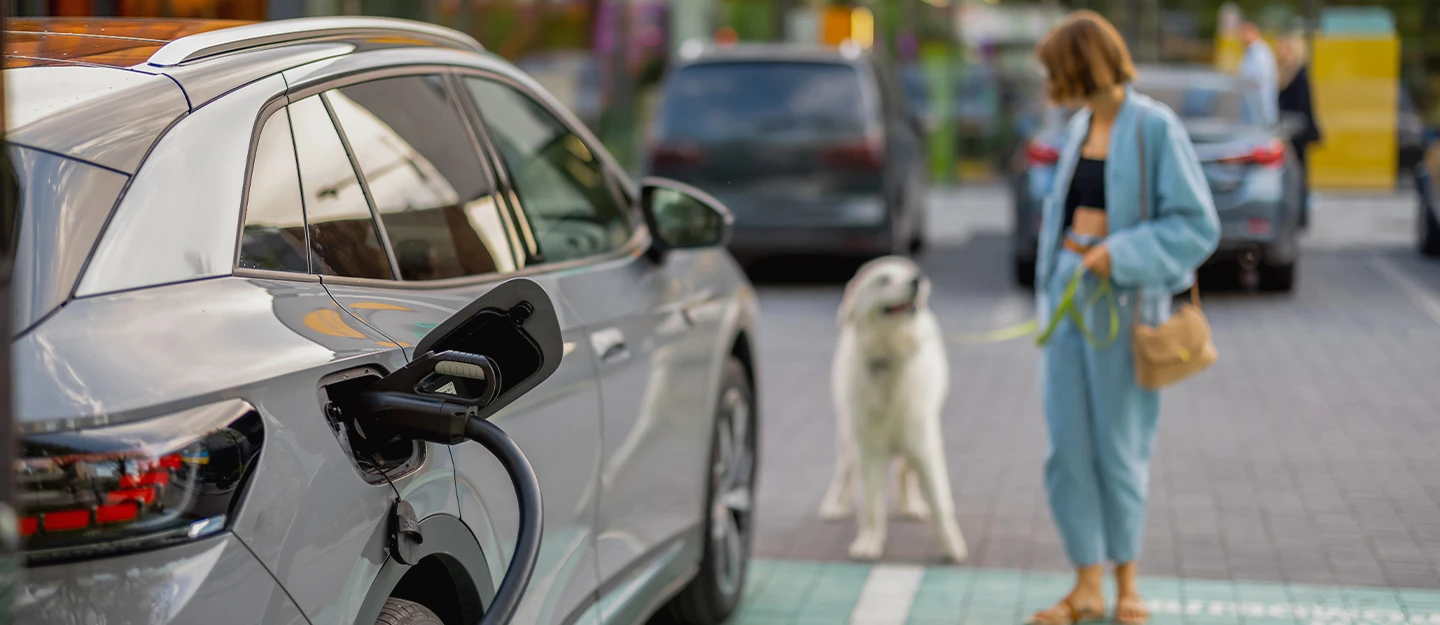 Woman loading shopping into her White Tesla while using a public EV Charging station 