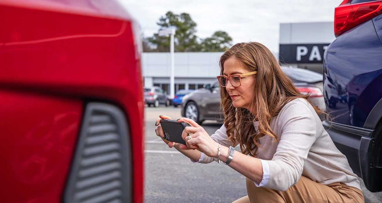 Woman inspecting vehicle with smart phone