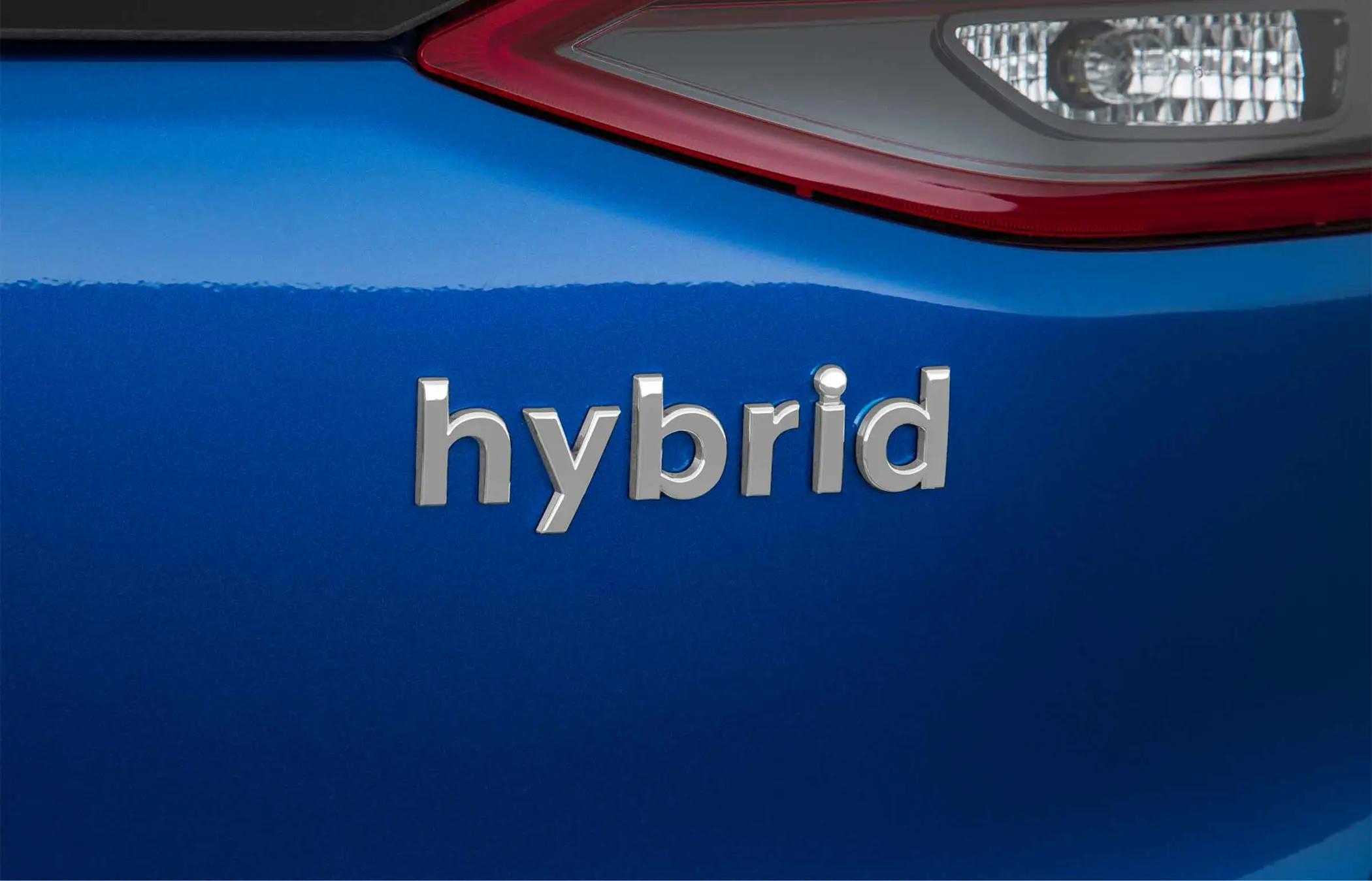 Close-up of the word 'hybrid' displayed on the rear of a blue car
