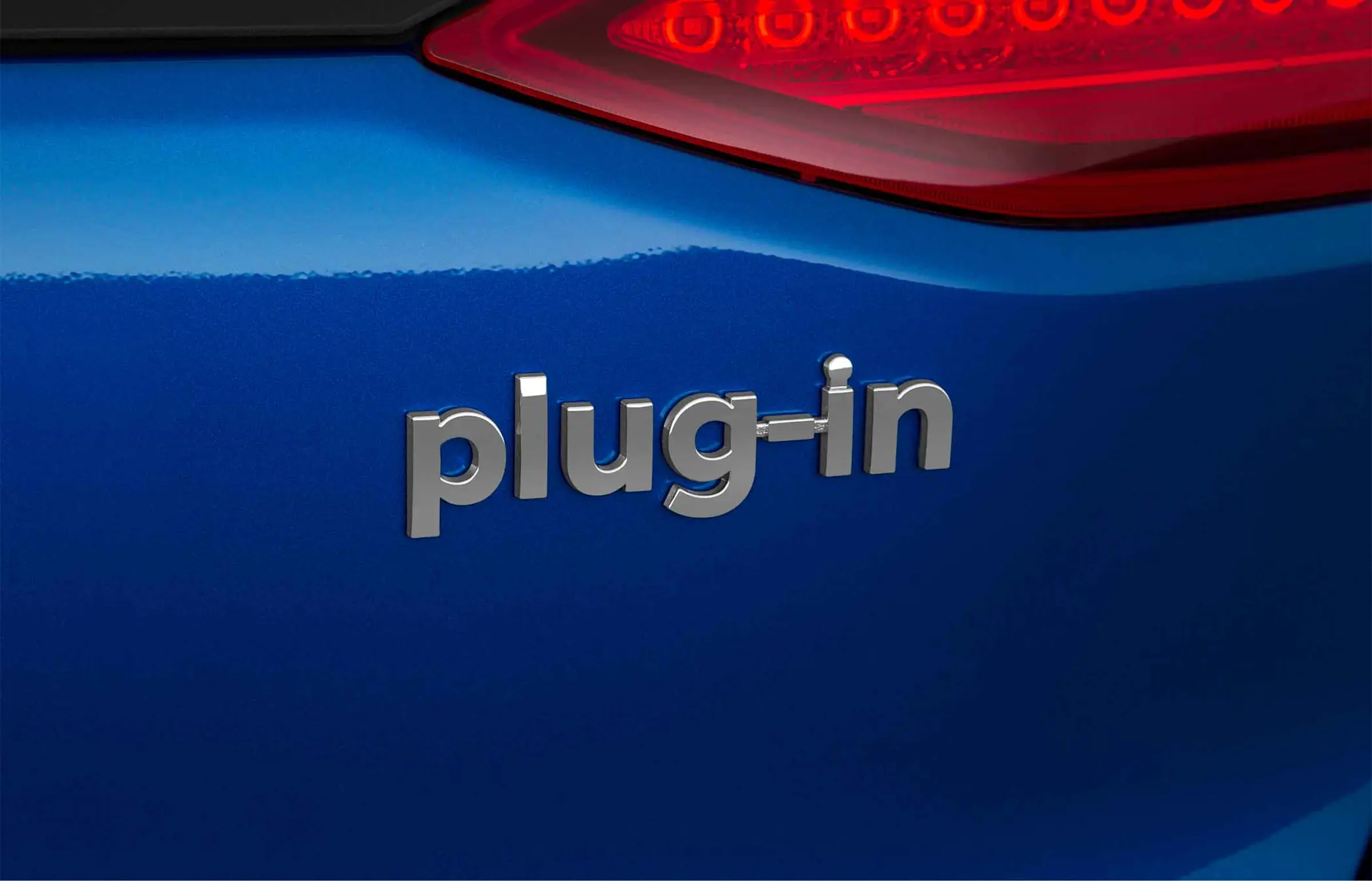 Close-up of the word 'plug-in displayed on the rear of a blue car