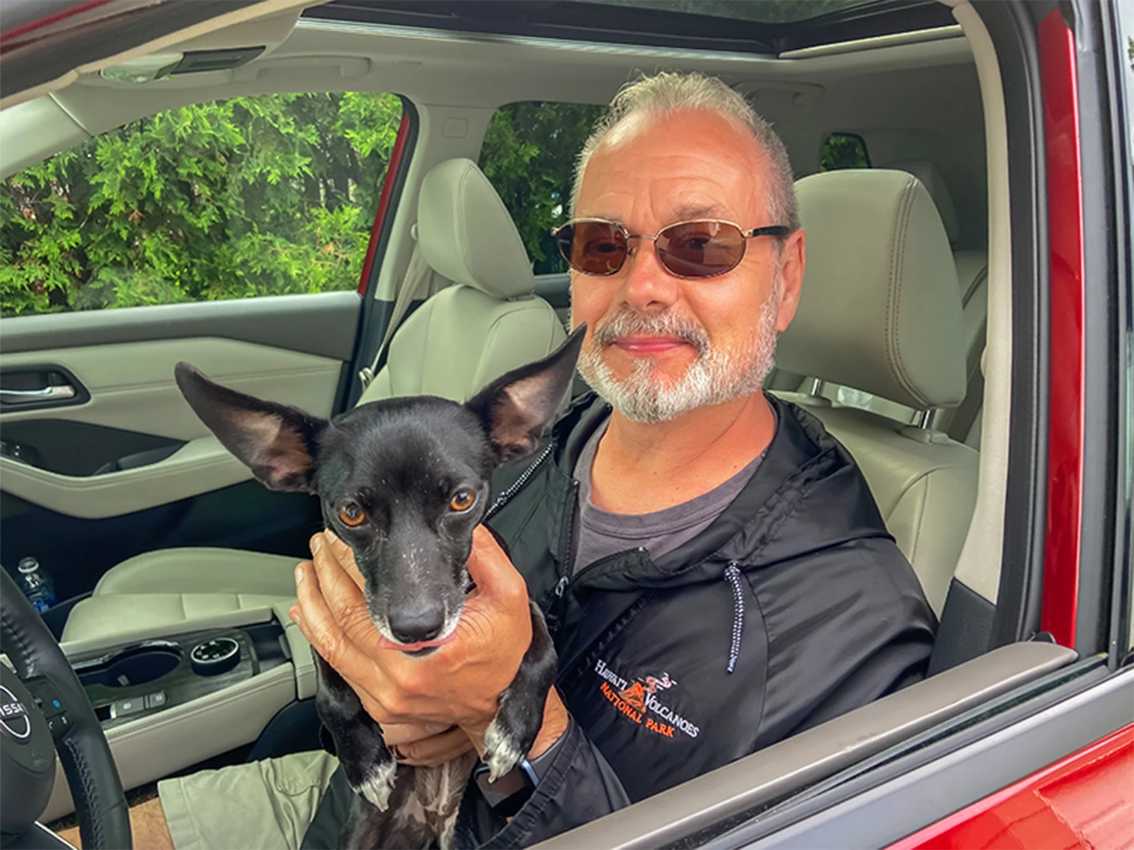CarMax customer William sitting with his dog in the drivers seat of his 2022 Nissan Rogue SL