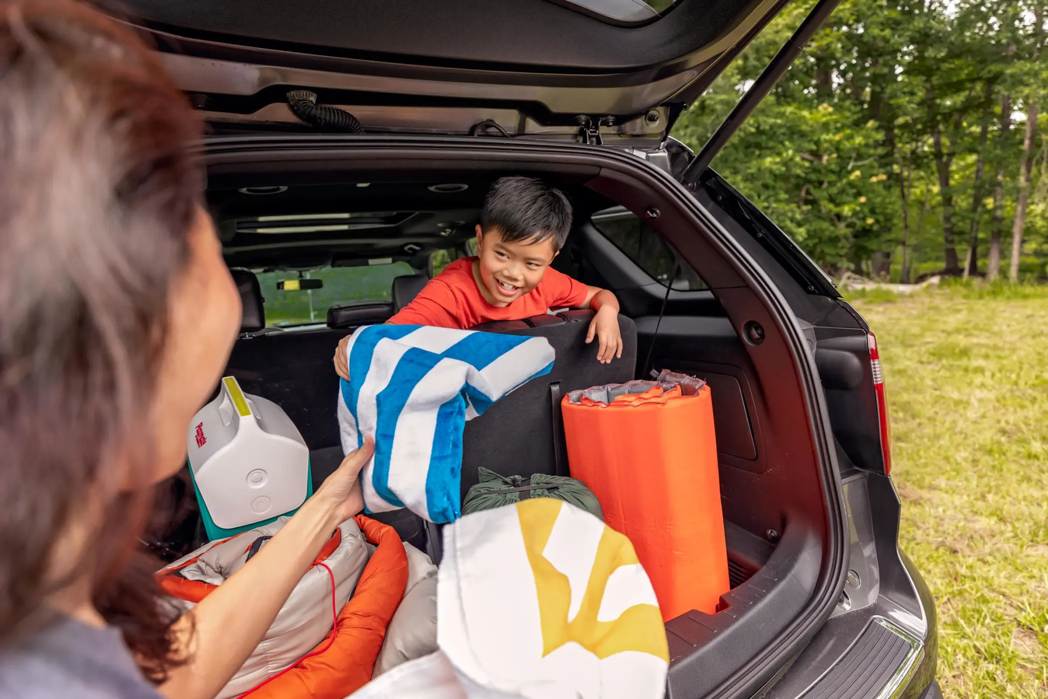 Boy in back of SUV smiling at woman in foreground