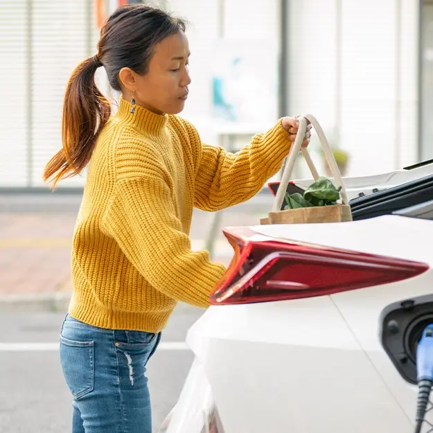 woman loads groceries into back of her EV while it charges