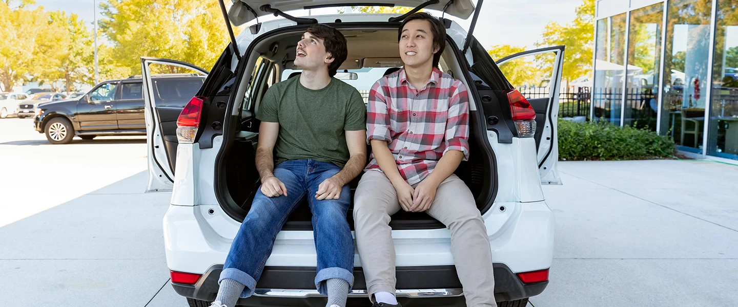 Two friends sitting in the trunk of a white SUV 