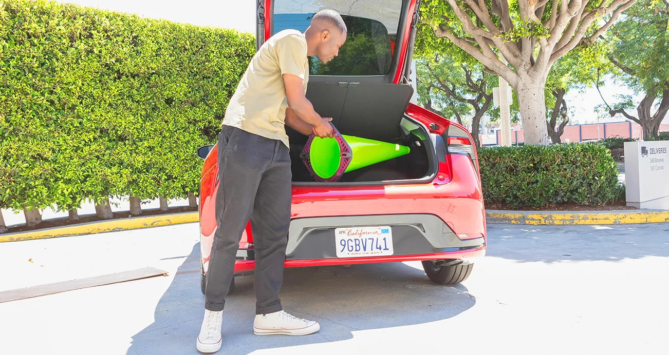 Man placing green traffic cone in frunk of Toyota Prius