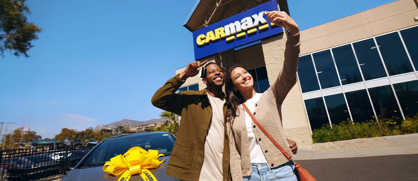 Customer smiling as she sits with a CarMax associate reviewing her CarMax purchase options in-store