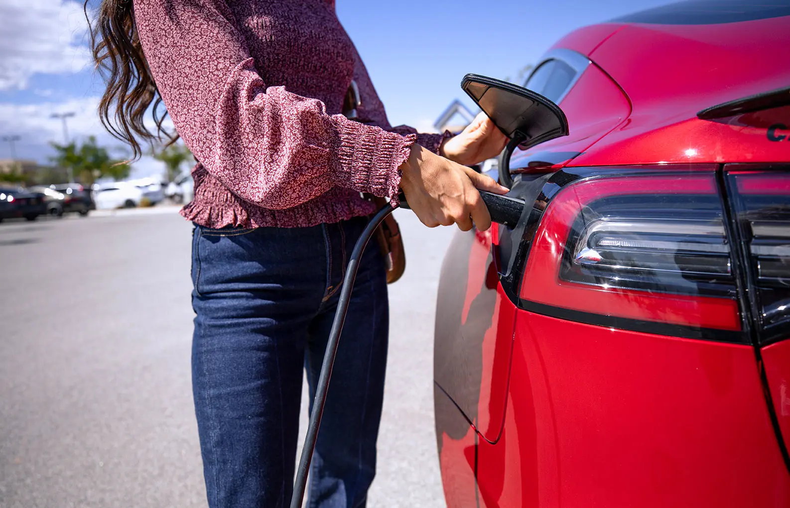 woman plugging in a red EV