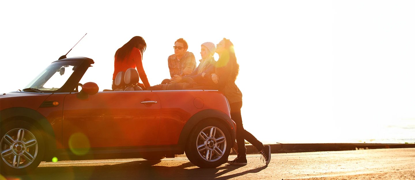 Friends standing around red mini copper convertible