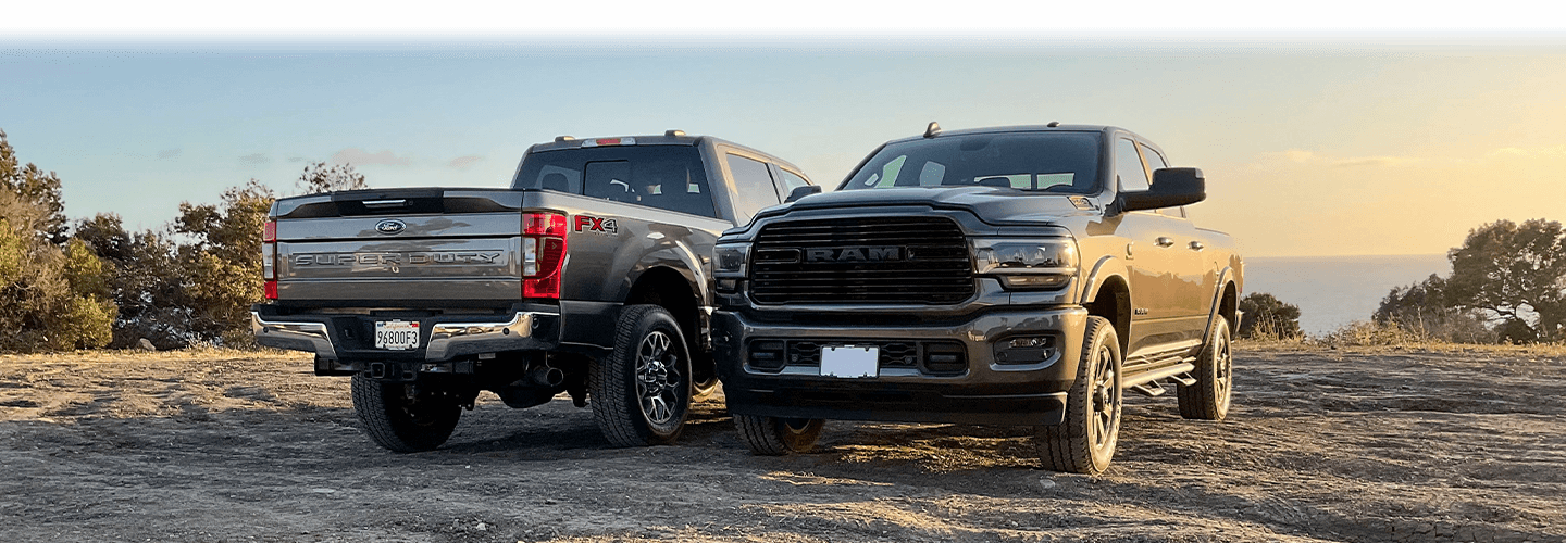 Ford F-250 and Ram 2500 parked in rocky area by a body of water