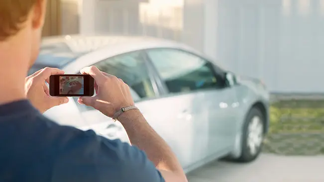 How to Sell Your Car: Man taking photo of silver hatchback | CarMax