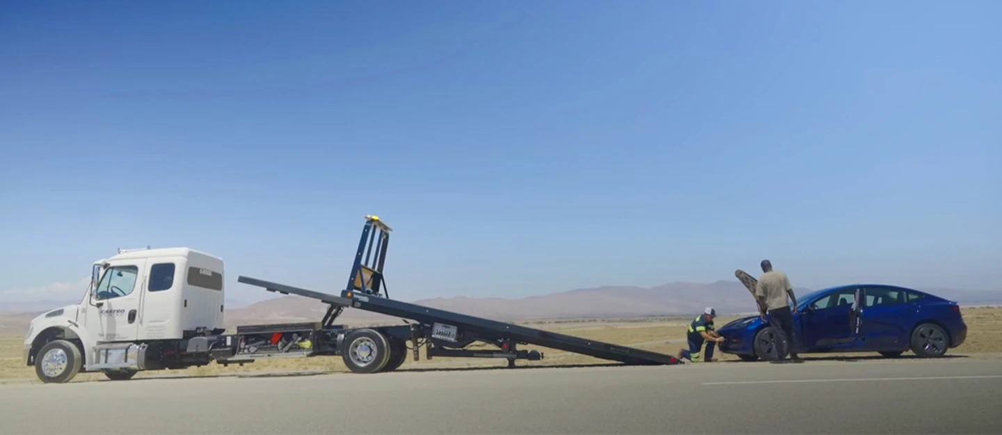 Electric vehicle being loaded onto a transport vehicle after battery runs out in a desert location