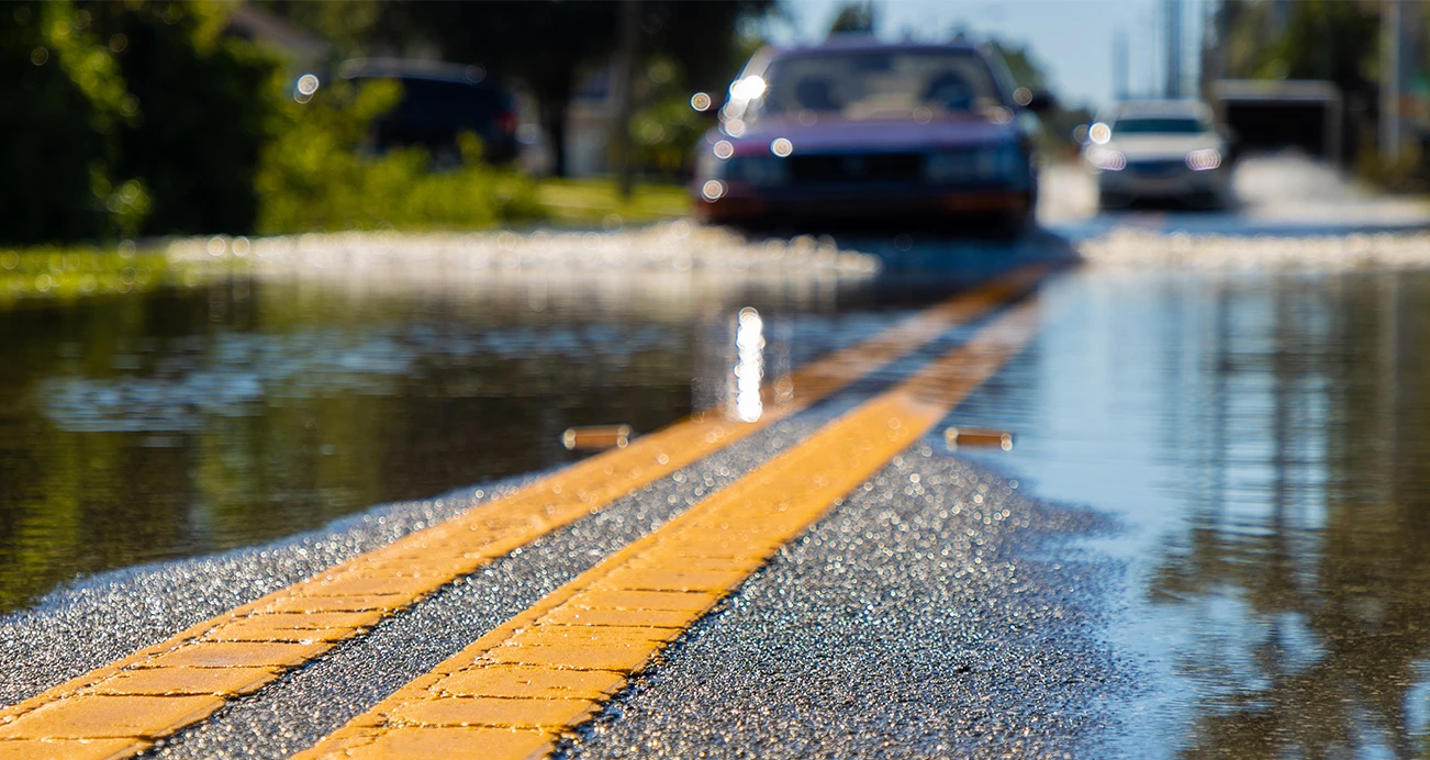 Close up of road markers in flood cars driving through water in background