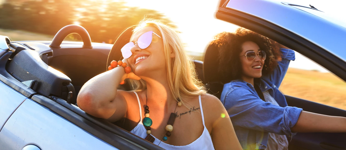 Two friends driving as the sun sets in their convertible sports car