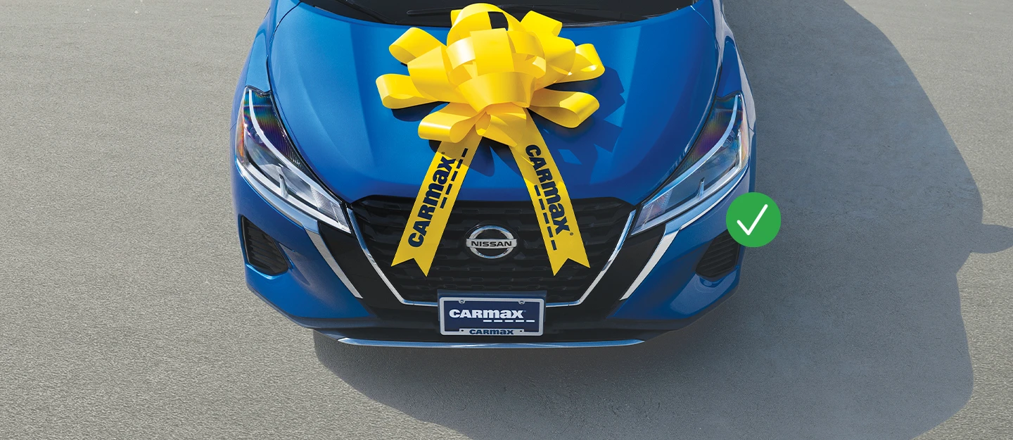 Blue Nissan with CarMax yellow bow on hood