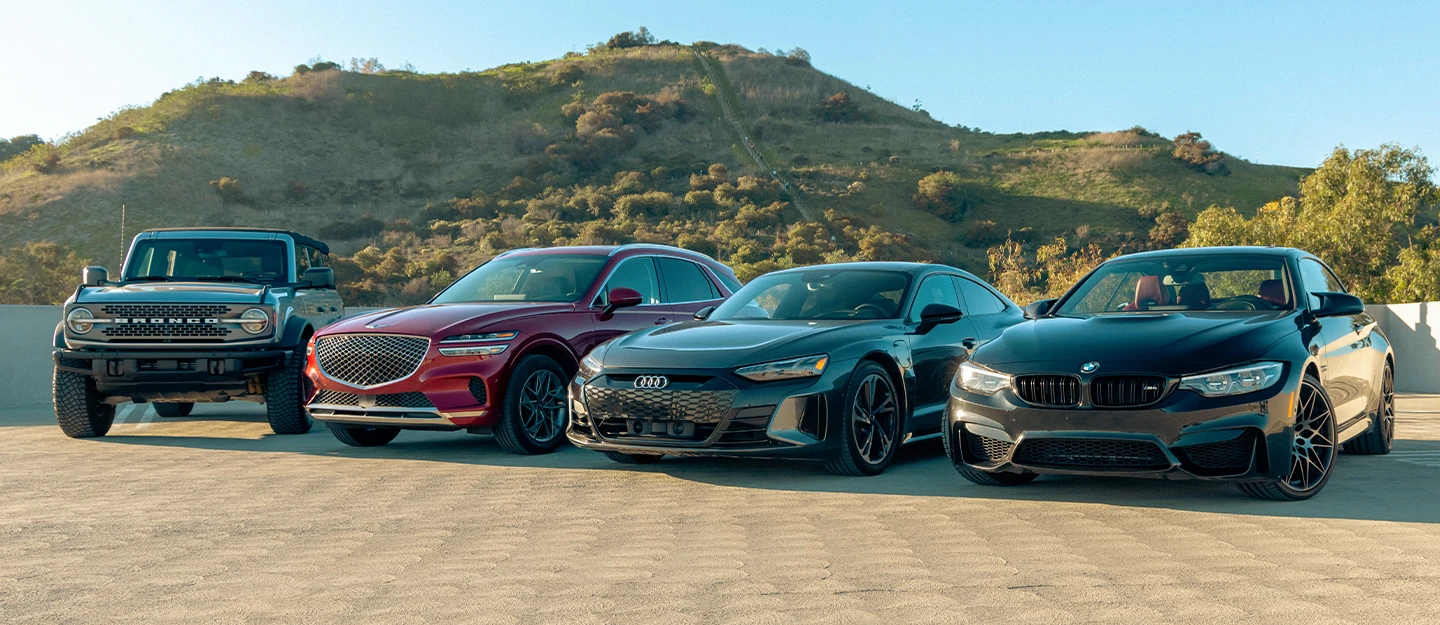 Cars lined up on a sandy valley: Ford Bronco, Genesis GV70, Audi E-tron GT, BMW M4