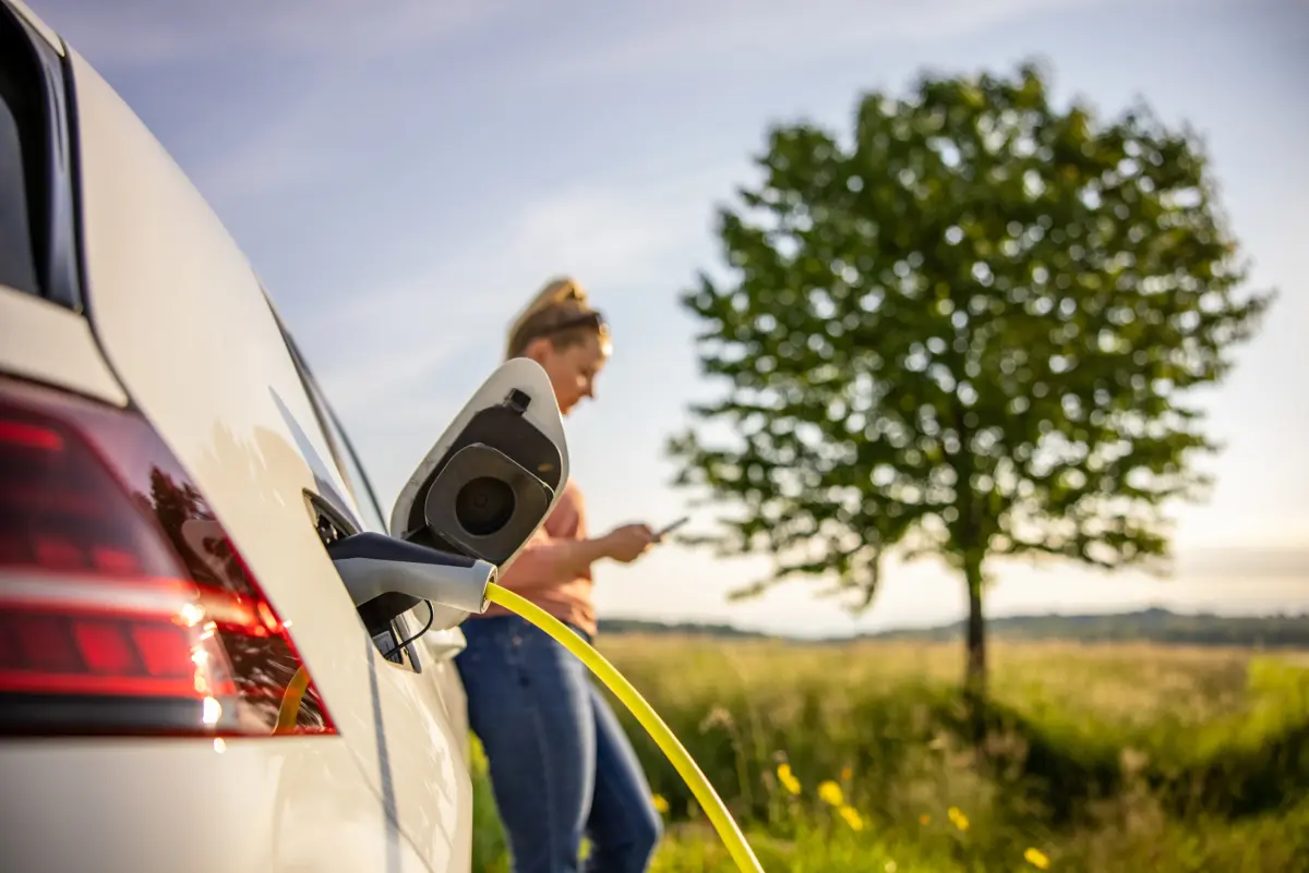 Can an EV fit my lifestyle? Image of woman on smartphone while charging an EV