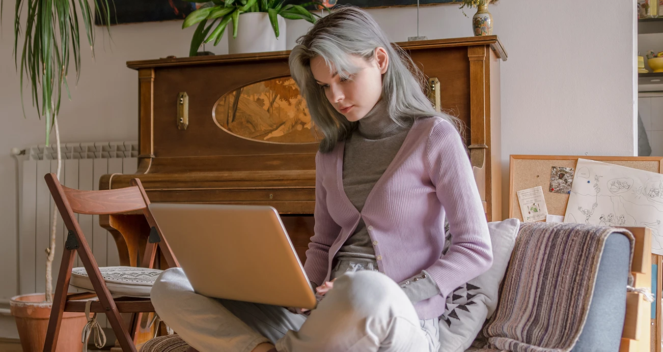 Woman sitting cross legged with laptop on her knees as she checks her credit from her living room 