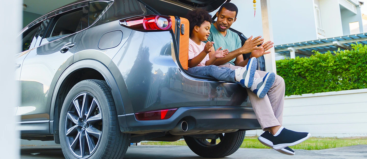 A man and a girl unpacking birthday presents and balloons out of the back of an SUV