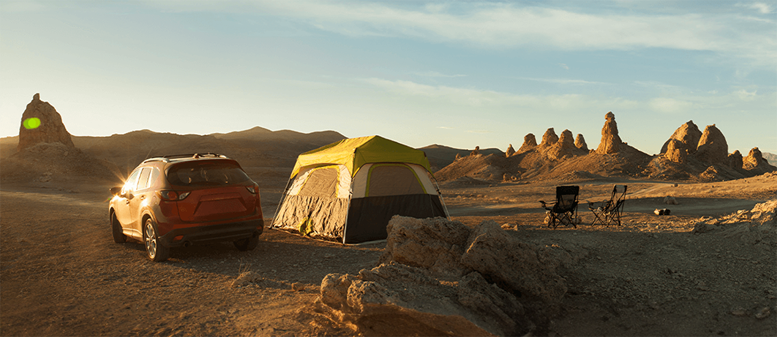 AWD vehicle parked beside tent in desert camping area