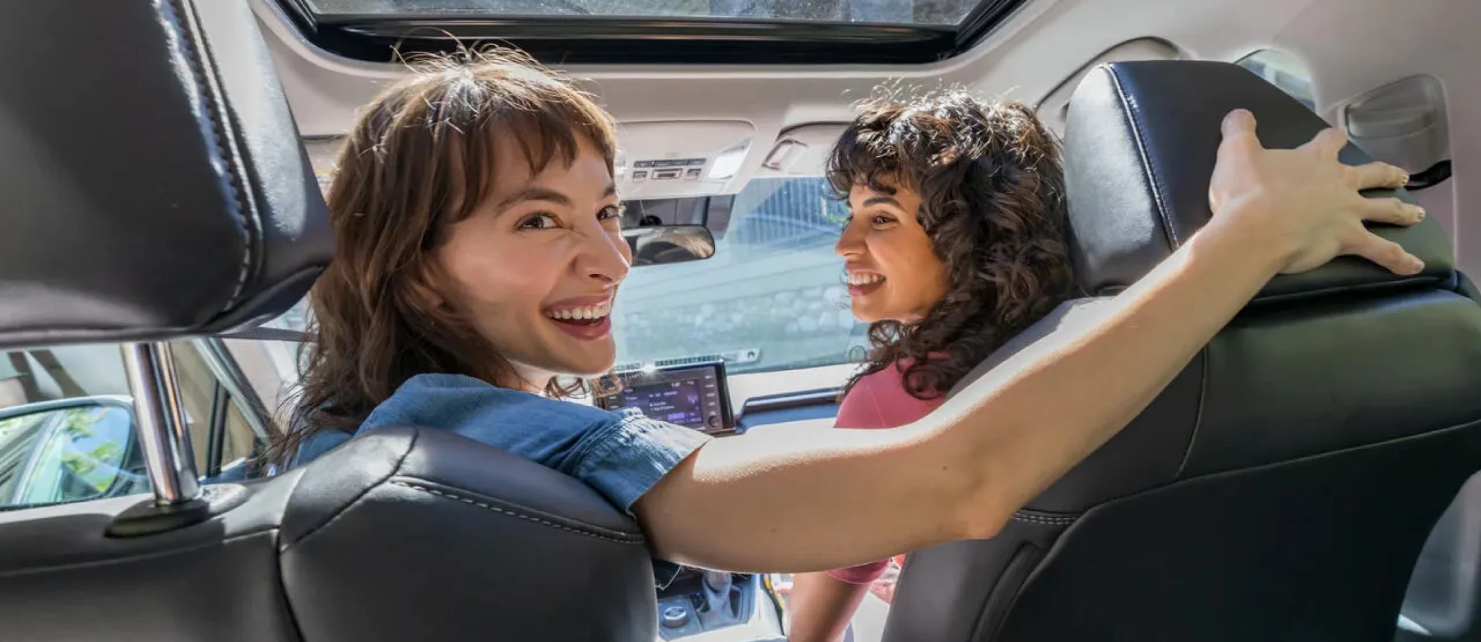 Two happy women in an SUV turning around to back up the vehicle