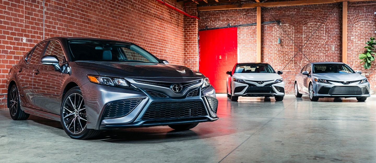 3 2023 Toyota Camry's lined up in different trim levels: 2023 Toyota Camry XSE, 2023 Toyota Camry SE and 2023 Toyota Camry LE