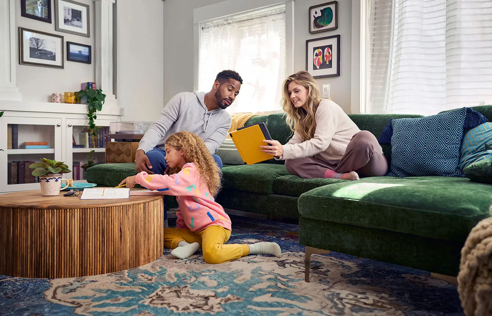 Family in living room with woman leaning towards man sharing her tablet