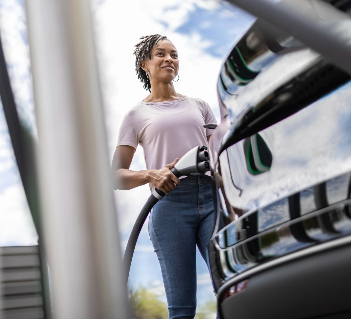 Woman walking towards EV with EV charger in hand