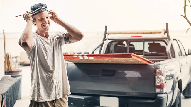 Man loading lumber into the back of his pickup truck