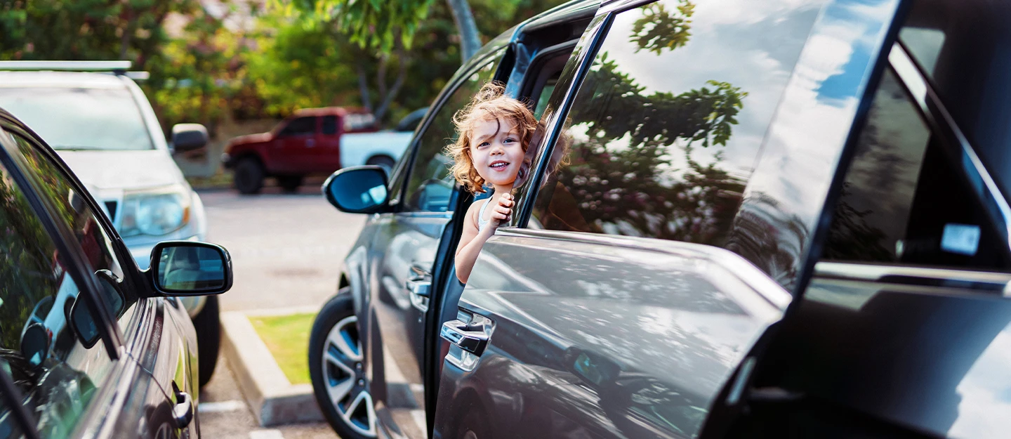 Little girl opening door of parked grey Honda Odyssey 