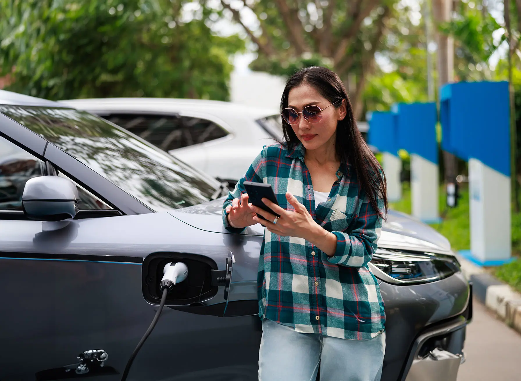 Woman multitasking on phone while EV is charging