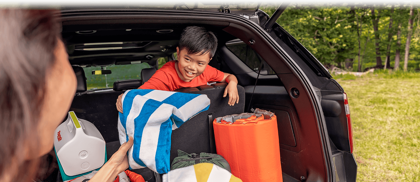 Family unpacking camping supplies from SUV